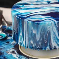 image of an ocean inspired white and blue mirror glaze cake