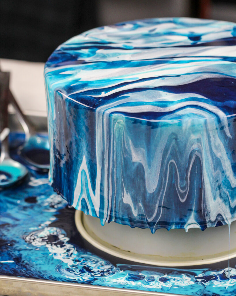 image of an ocean inspired white and blue mirror glaze cake
