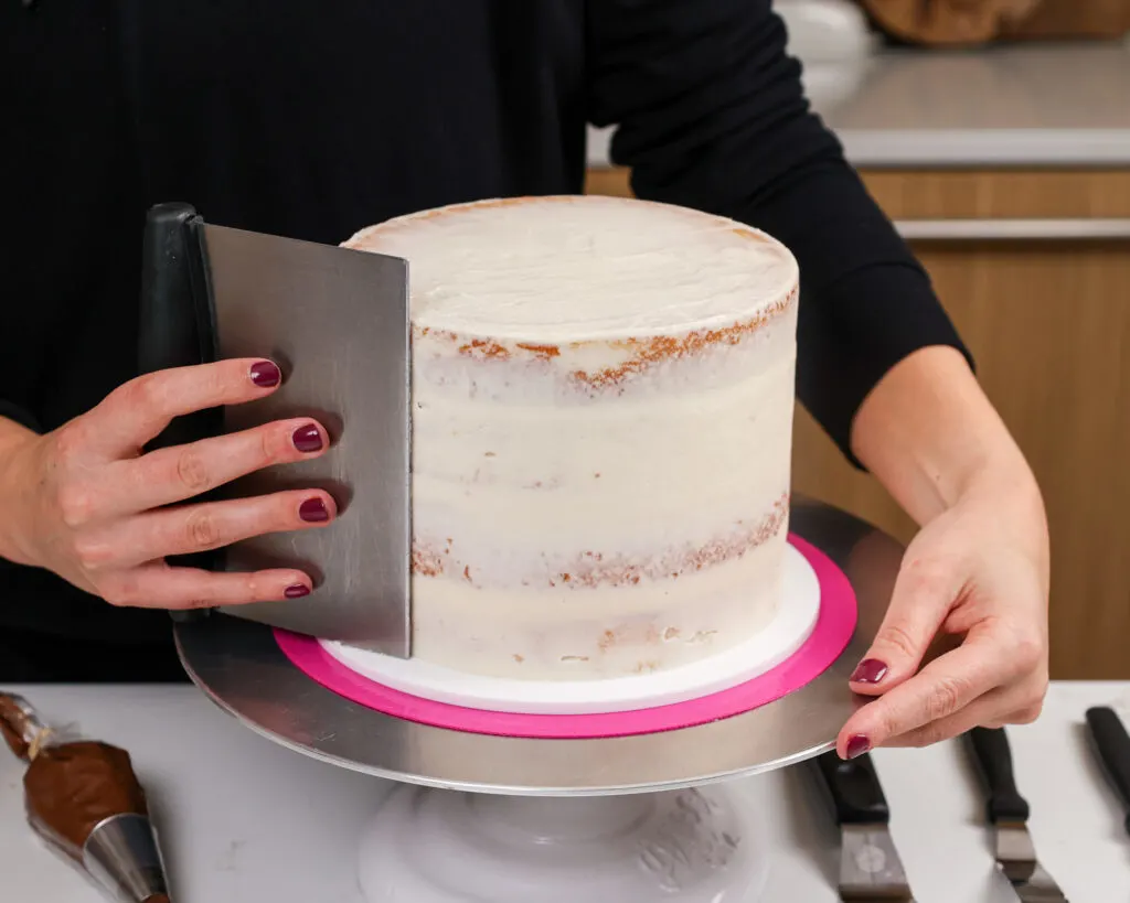 image of a 7-inch layer cake that's being crumb coated and smoothed with a bench scraper