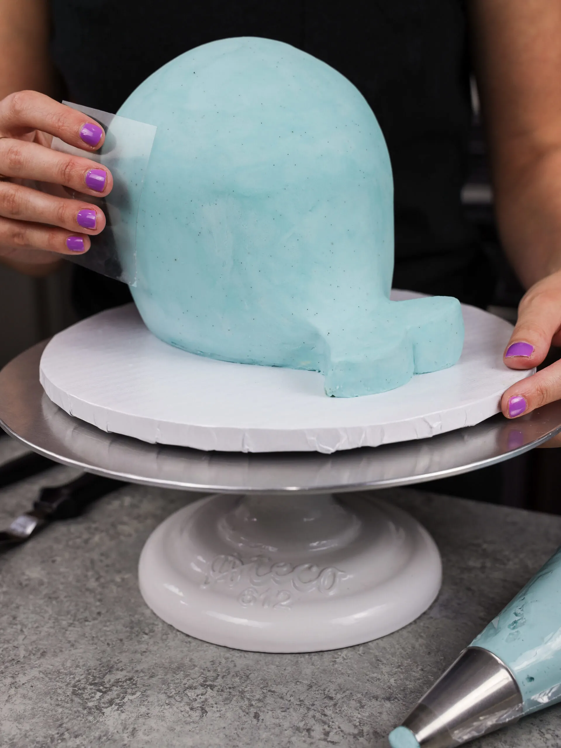image of blue buttercream being smoothed onto a narwhal cake
