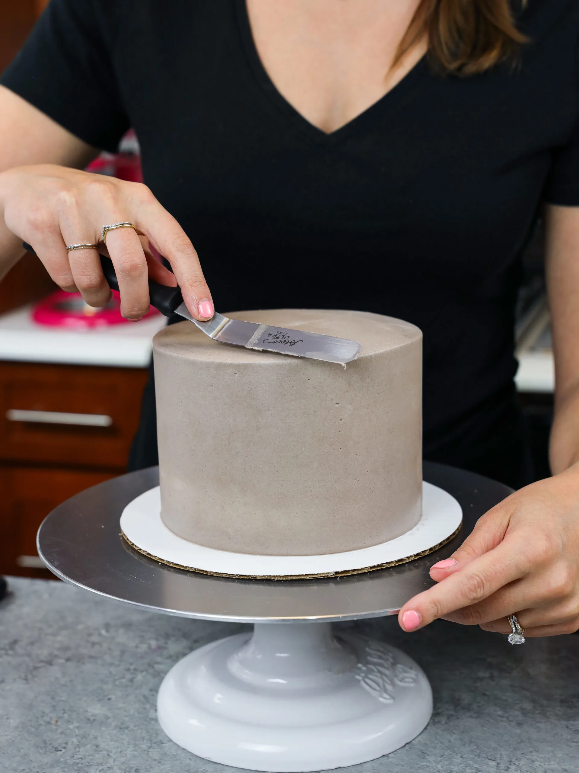 image of grey buttercream being smoothed onto a 6-inch cake