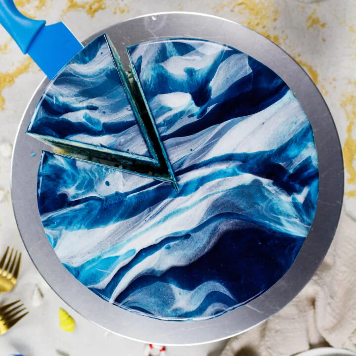 image of a blue marbled mirror glaze cake that's been cut into