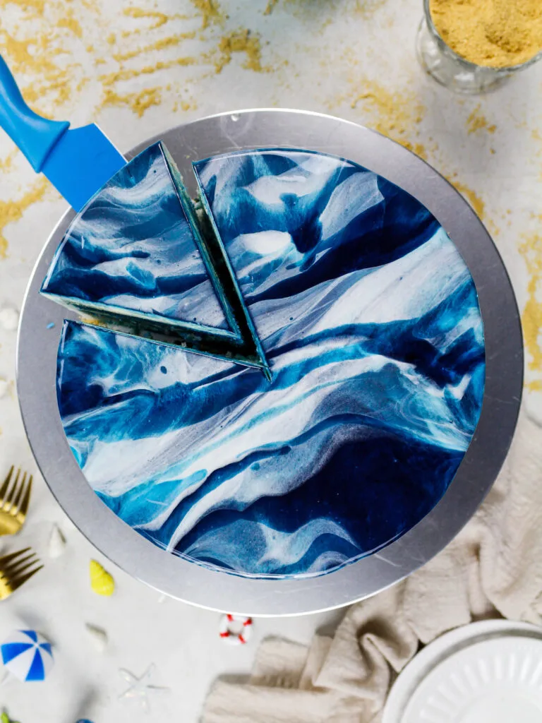 image of a blue marbled mirror glaze cake that's been cut into