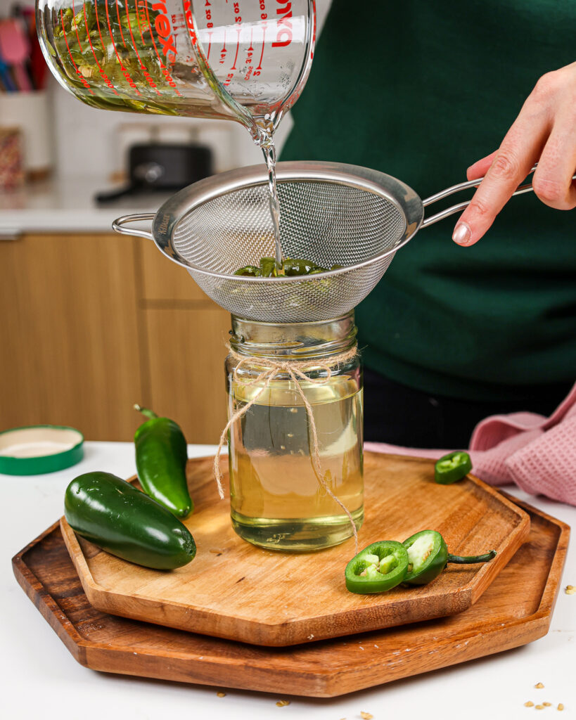 image of jalapeno simple syrup being poured through a sieve