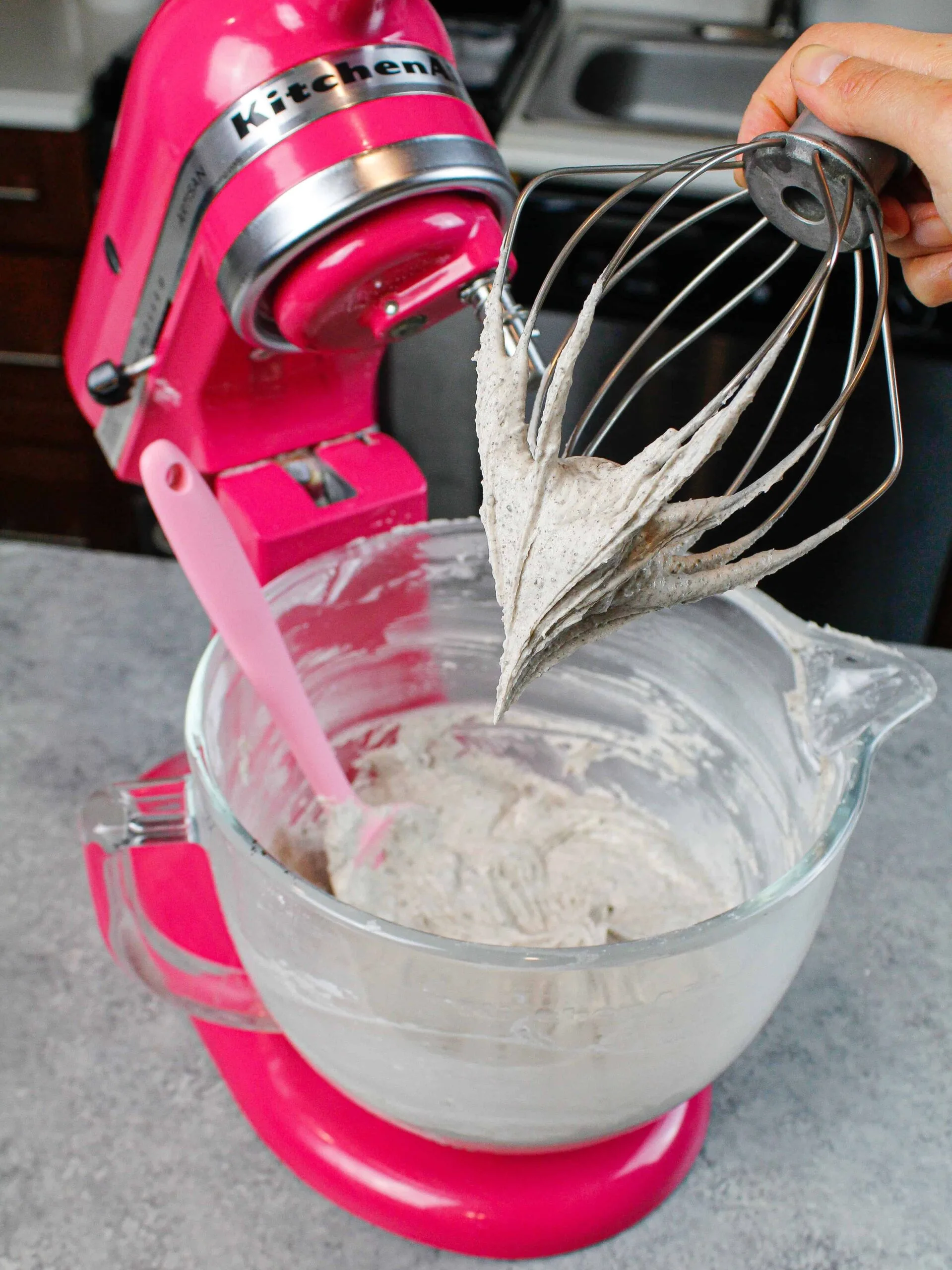image of oreo frosting on a whisk attachment, after just being made in a pink stand mixer