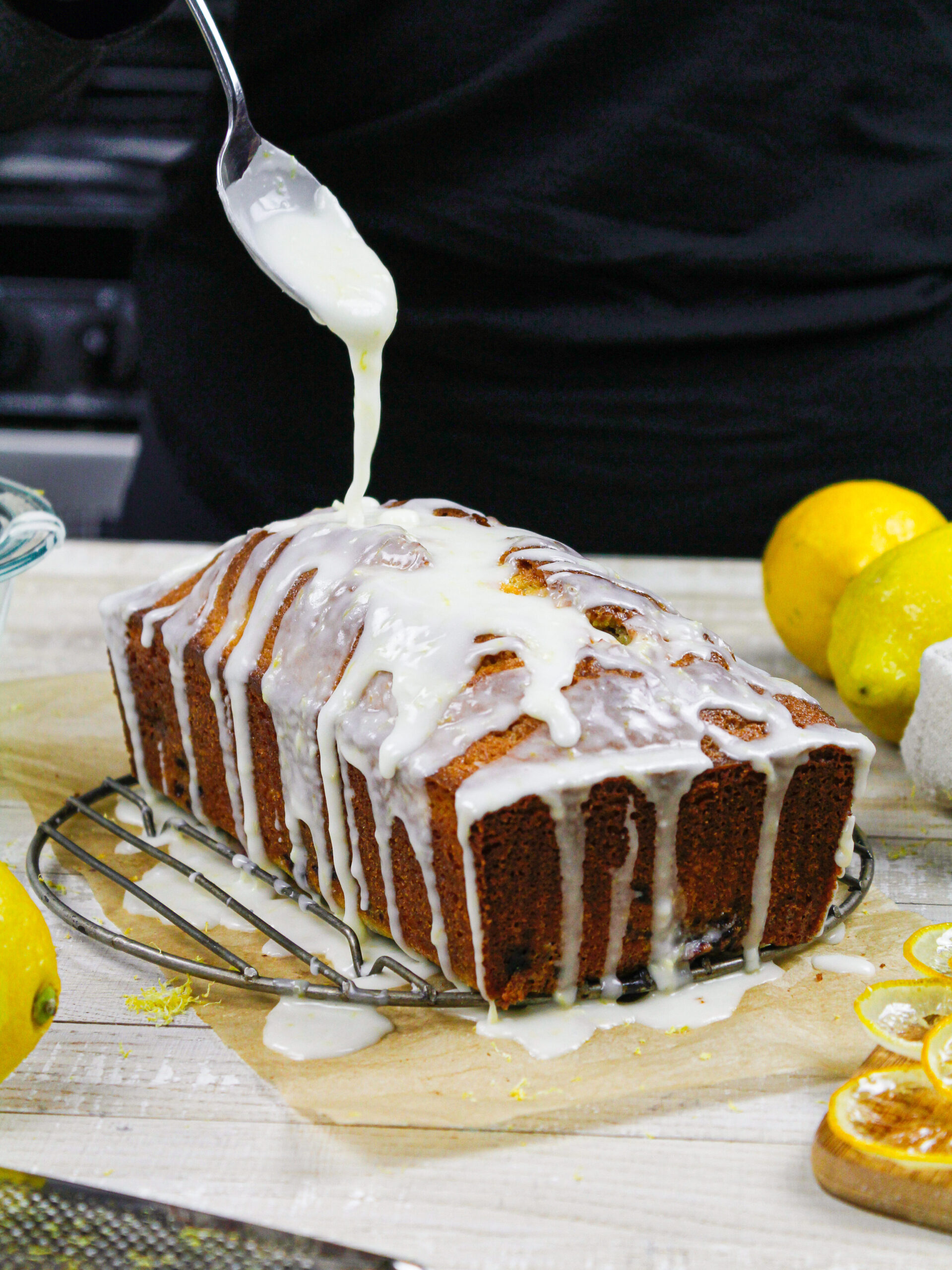 image of lemon glaze being drizzled over a blackberry loaf