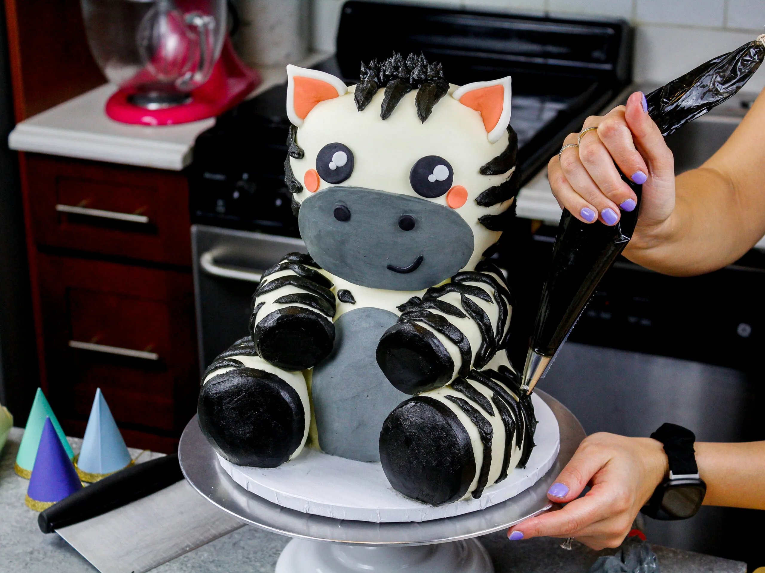 image of black buttercream frosting stripes being piped onto an adorable baby zebra cake made for a birthday party