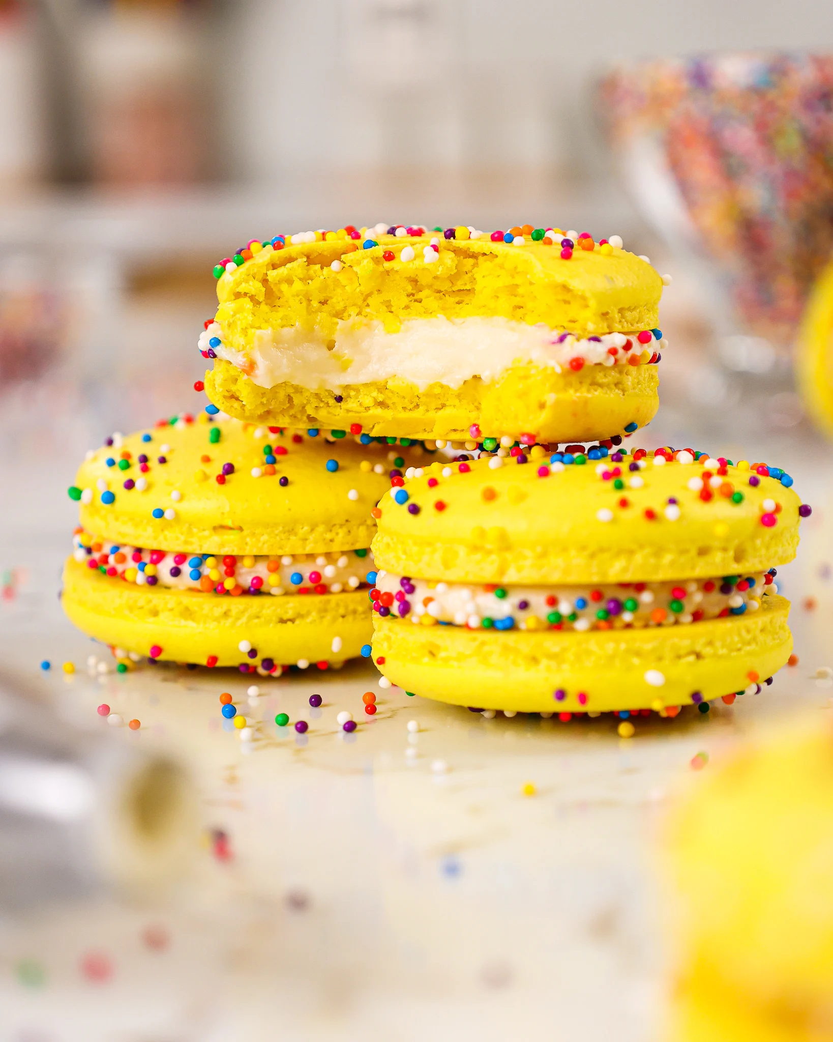 image of funfetti macarons being stacked on a plate that have been decorated with colorful nonpareil sprinkles