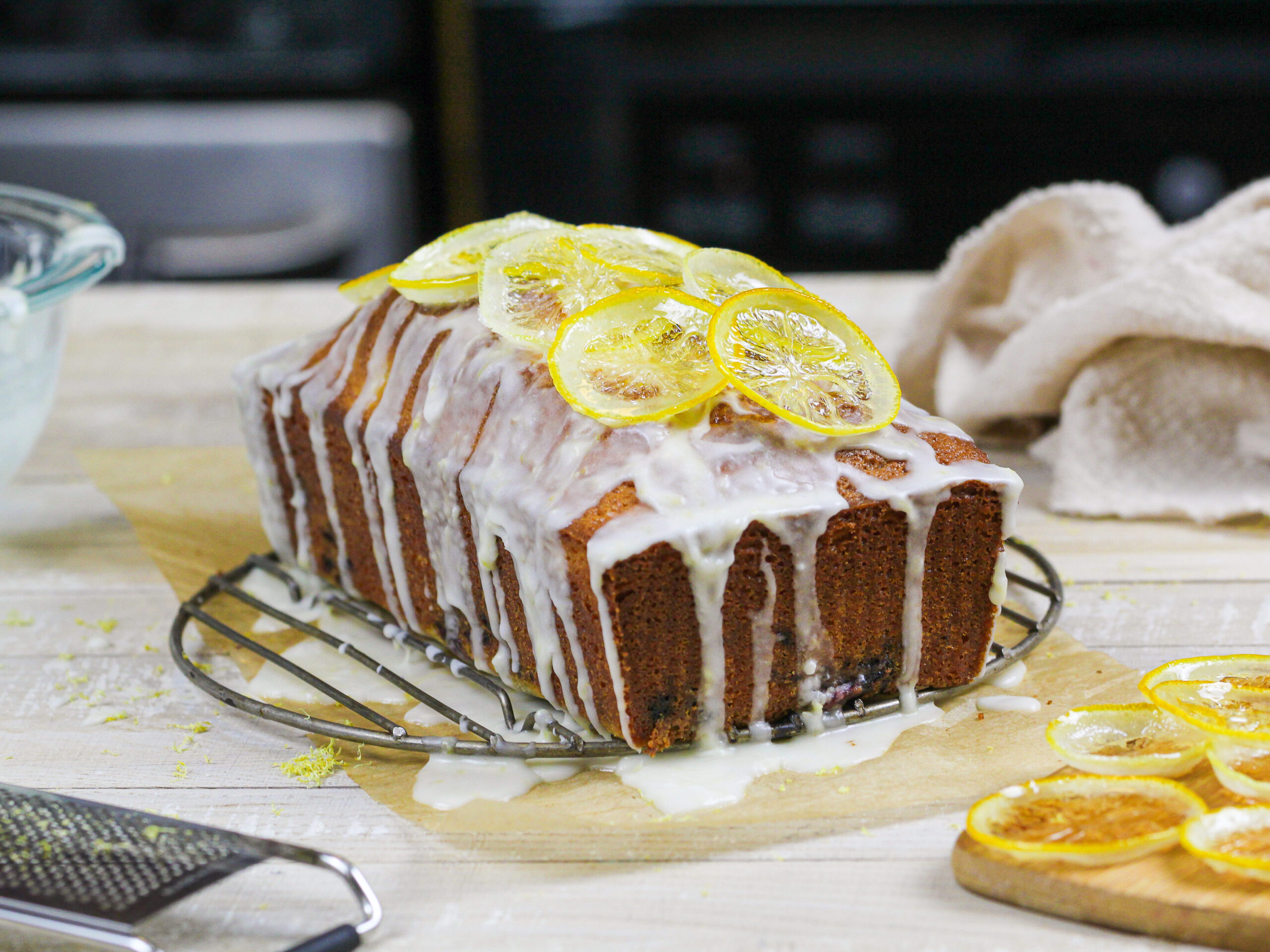 image of a blackberry lemon bread drizzled with lemon glaze and topped with candied lemons