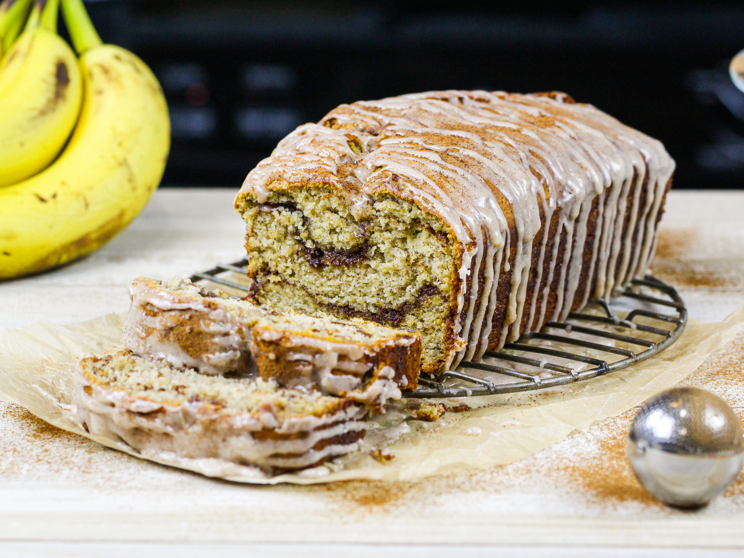 image of cinnamon swirl banana bread loaf that's been sliced into to show its beautiful cinnamon sugar swirls