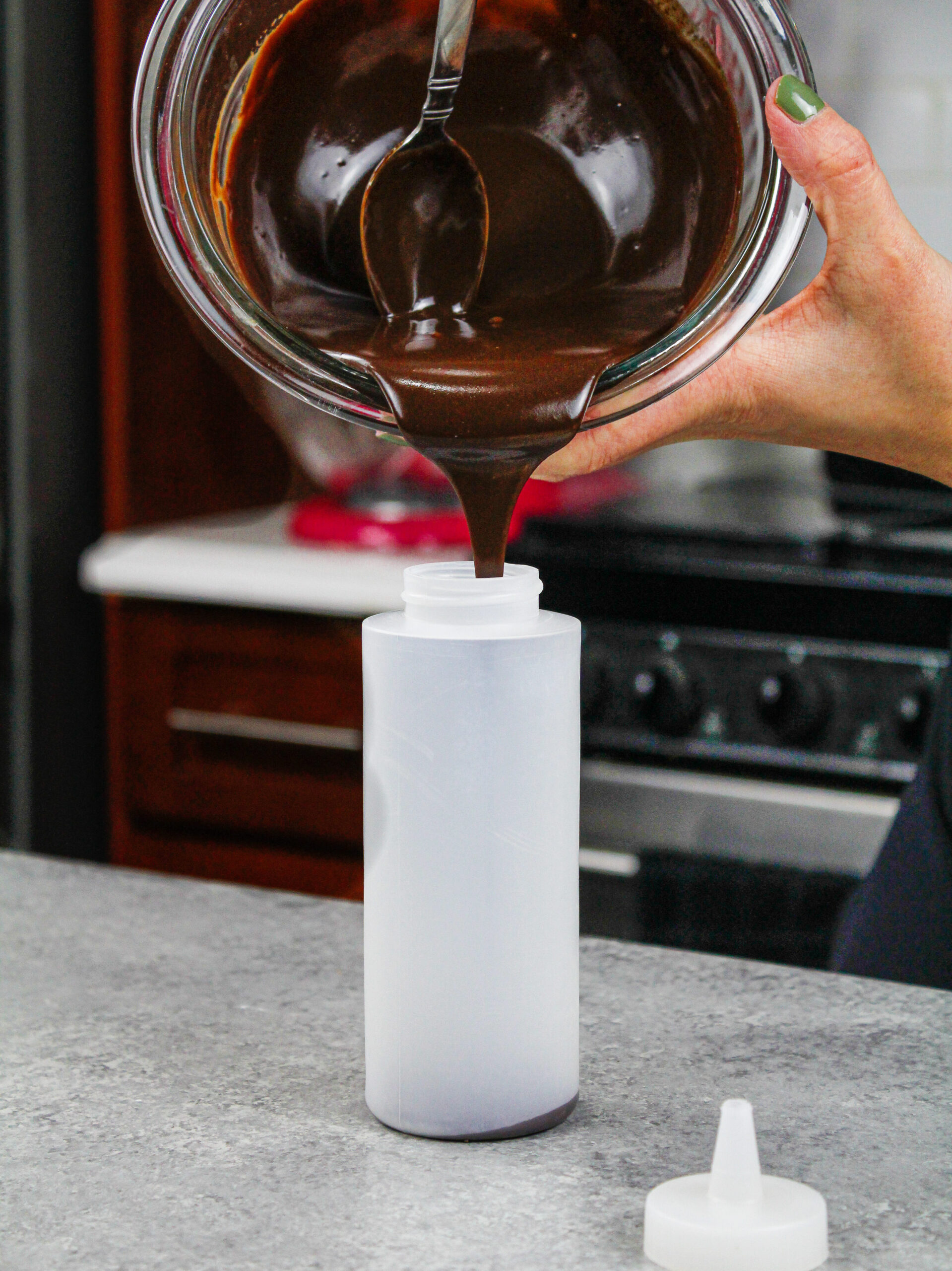 image of chocolate ganache being poured into a plastic squirt bottle to add drips to a cake