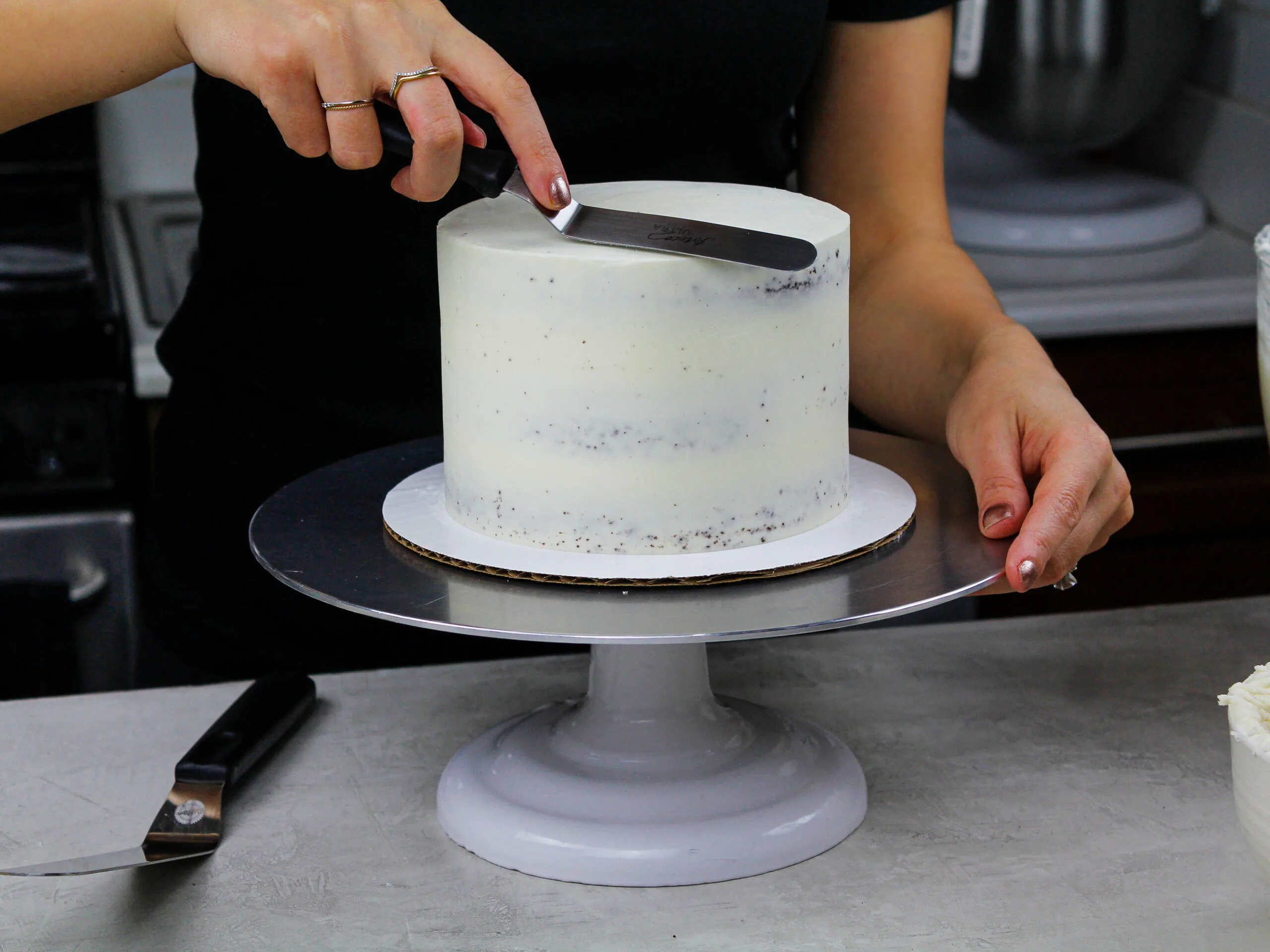 image of a chocolate being crumb coated with vanilla frosting to show How to Frost a Cake Smoothly