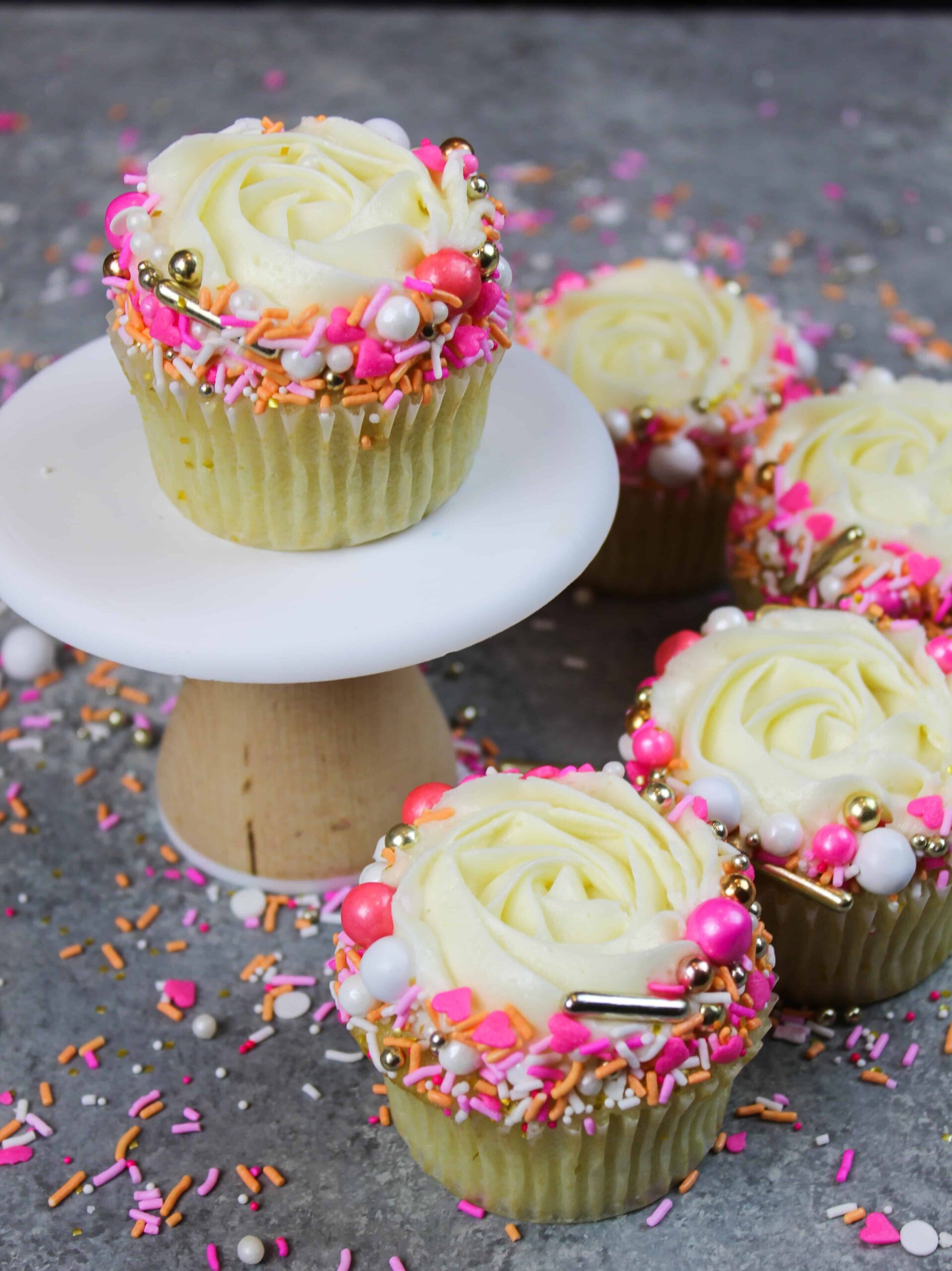 image of unwrapped vanilla cupcake decorated with a pretty sprinkle blend