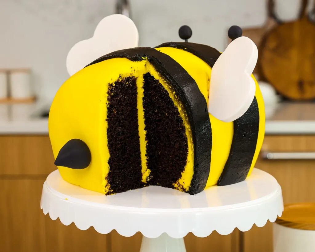 image of a bumblebee cake that's been cut into to show it's moist black cocoa cake layers and honey buttercream