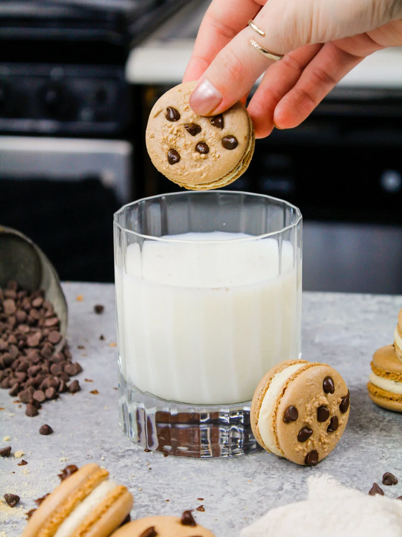 image of a cookie dough macaron being dipped into a glass of milk that was shared as part of a macaron round up post
