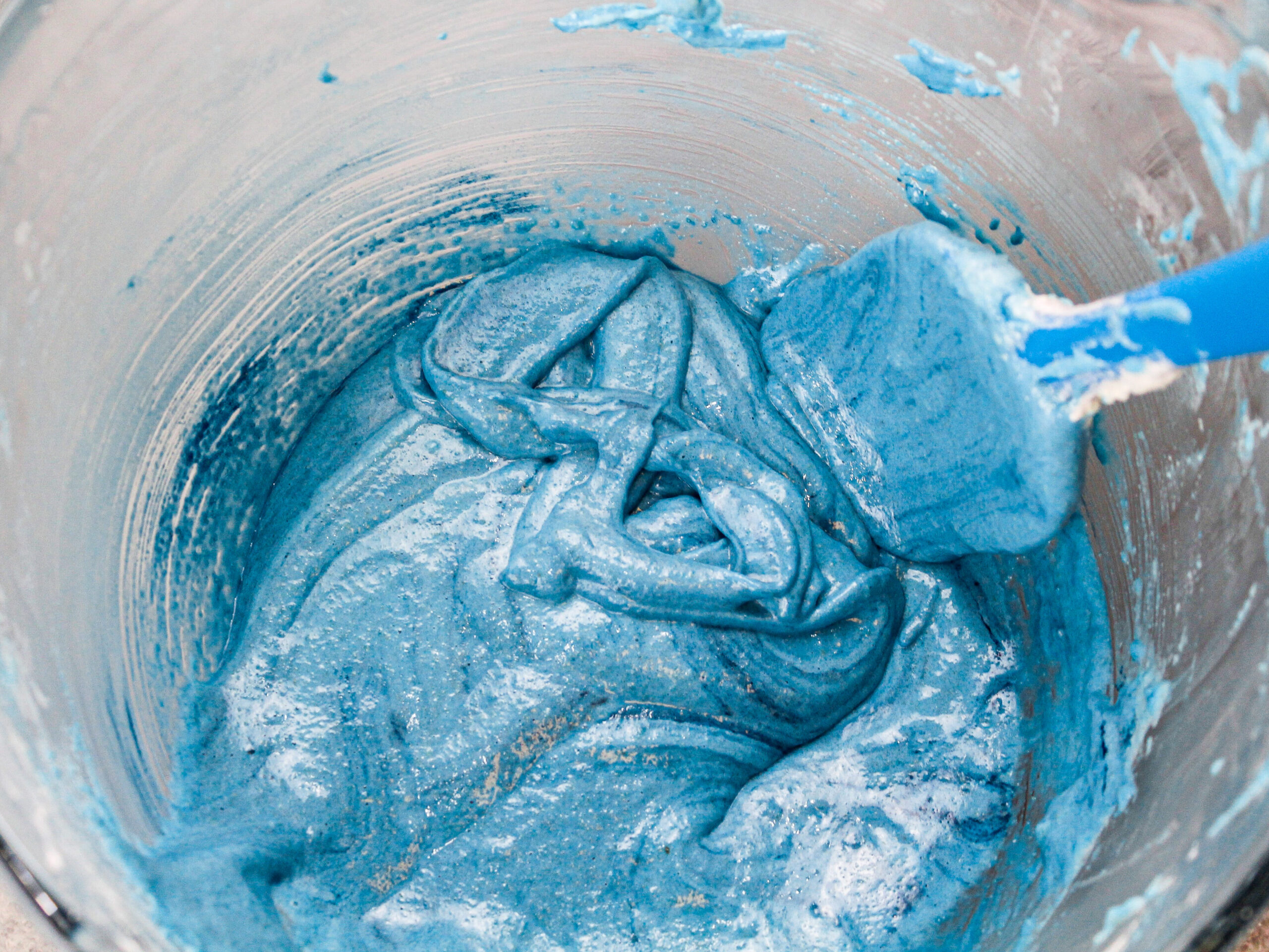 image of blueberry blue colored macaron batter that's been mixed to just the right consistency and can be used to draw figure 8s in the bowl as the batter flows off the spatula