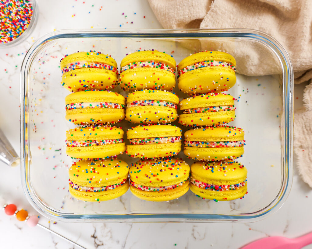 image of funfetti macarons in a container that have been rested in the fridge overnight