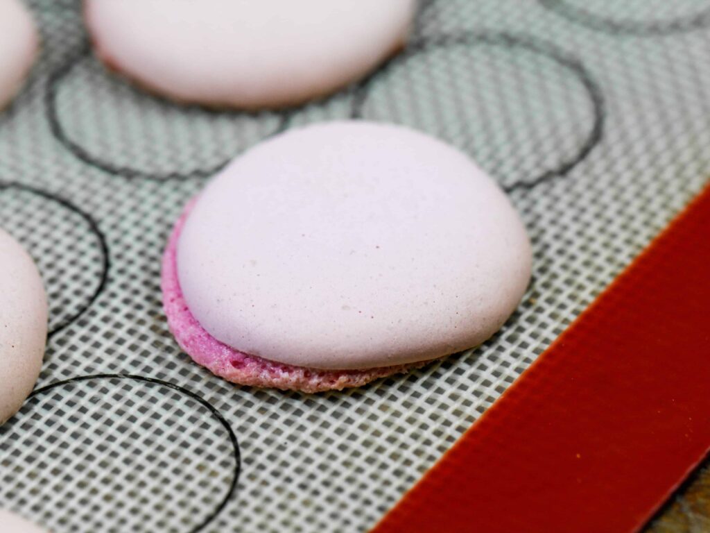 image of a macaron shell that baked with lopsided feet because the pan wasn't level