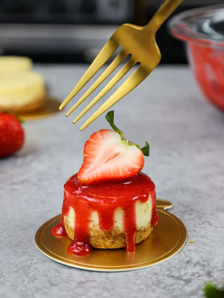 image of a mini strawberry cheesecake topped with a fresh strawberry garnish