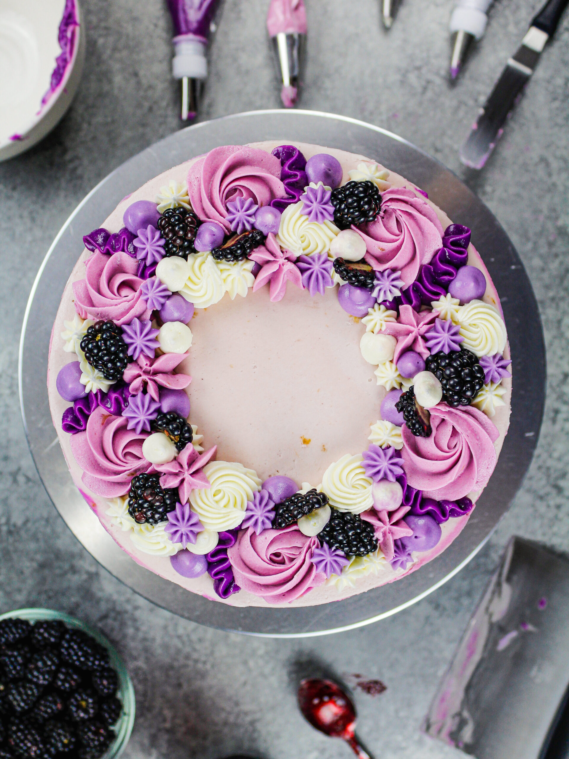 image of a pretty blackberry layer cake decorated with purple buttercream and fresh blackberries