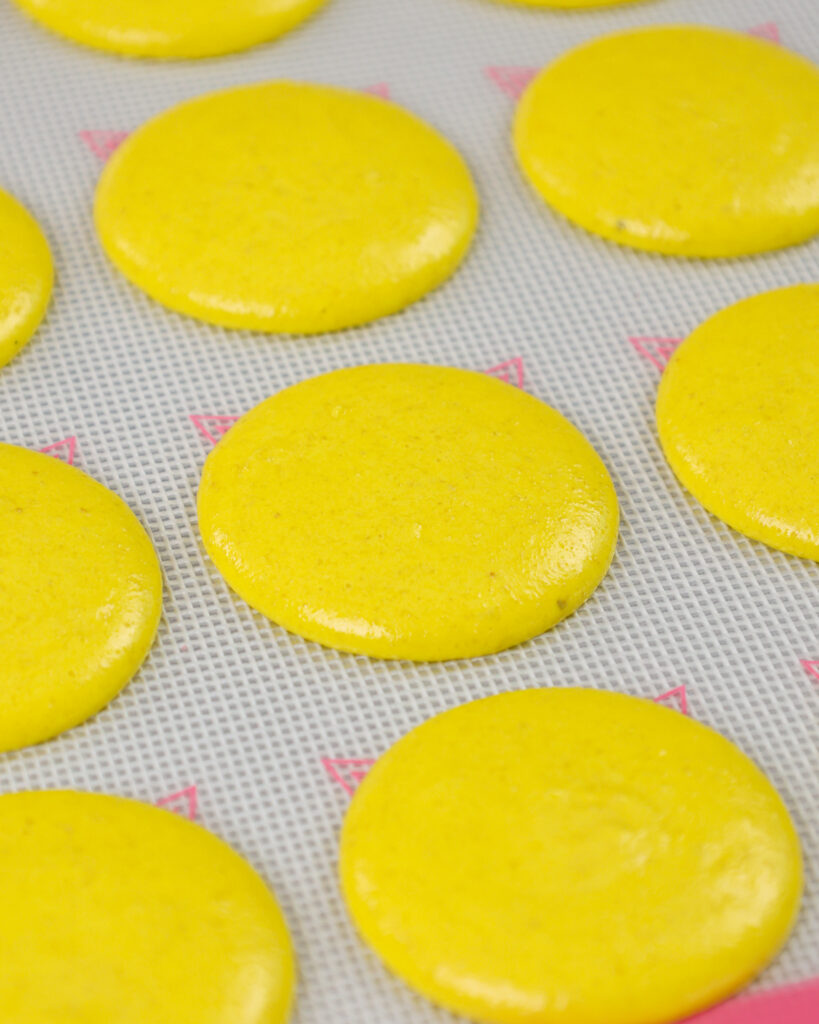 image of yellow macaron shells that have been piped and are ready to be rested