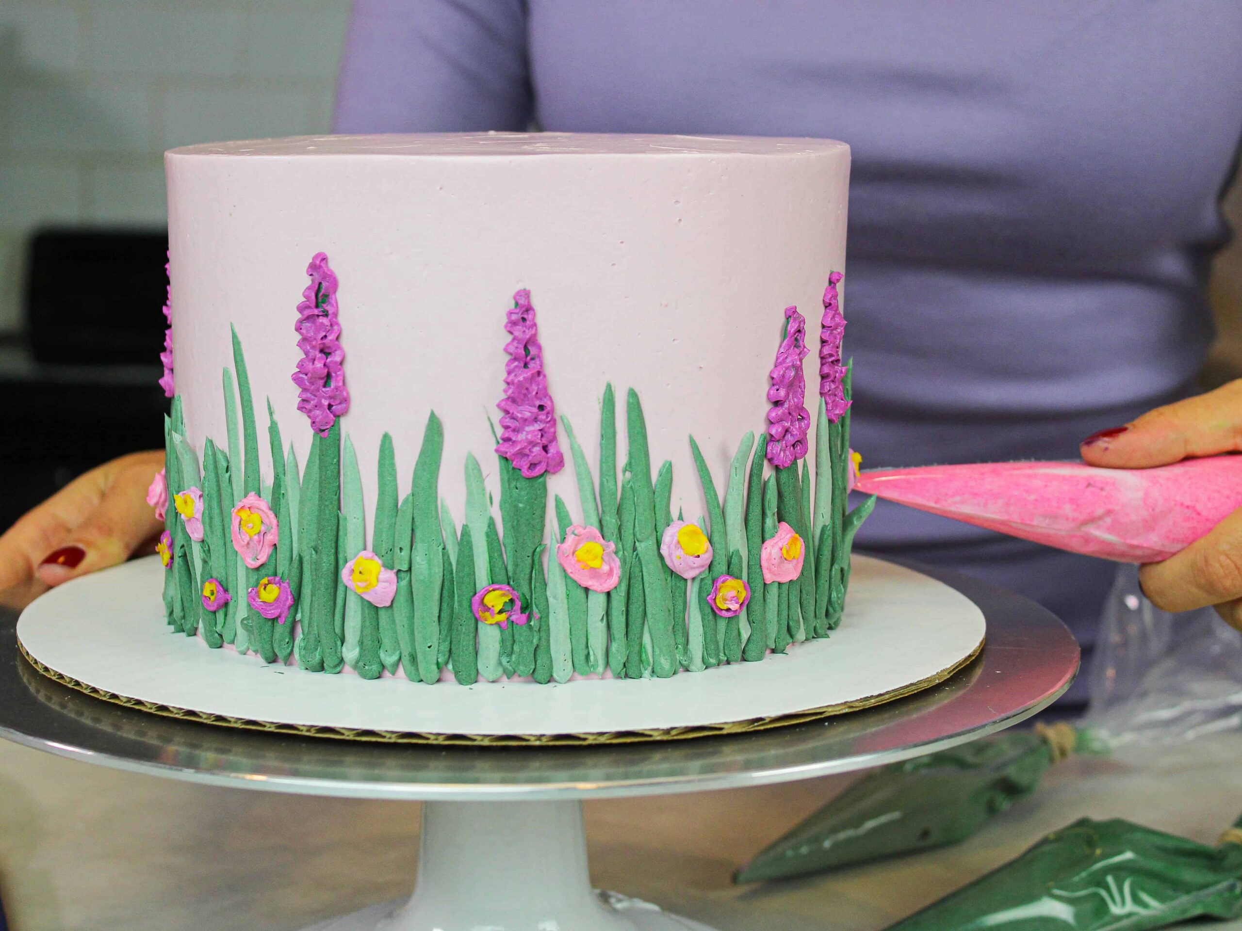 image of spring easter cake being decorated with swiss meringue buttercream flowers