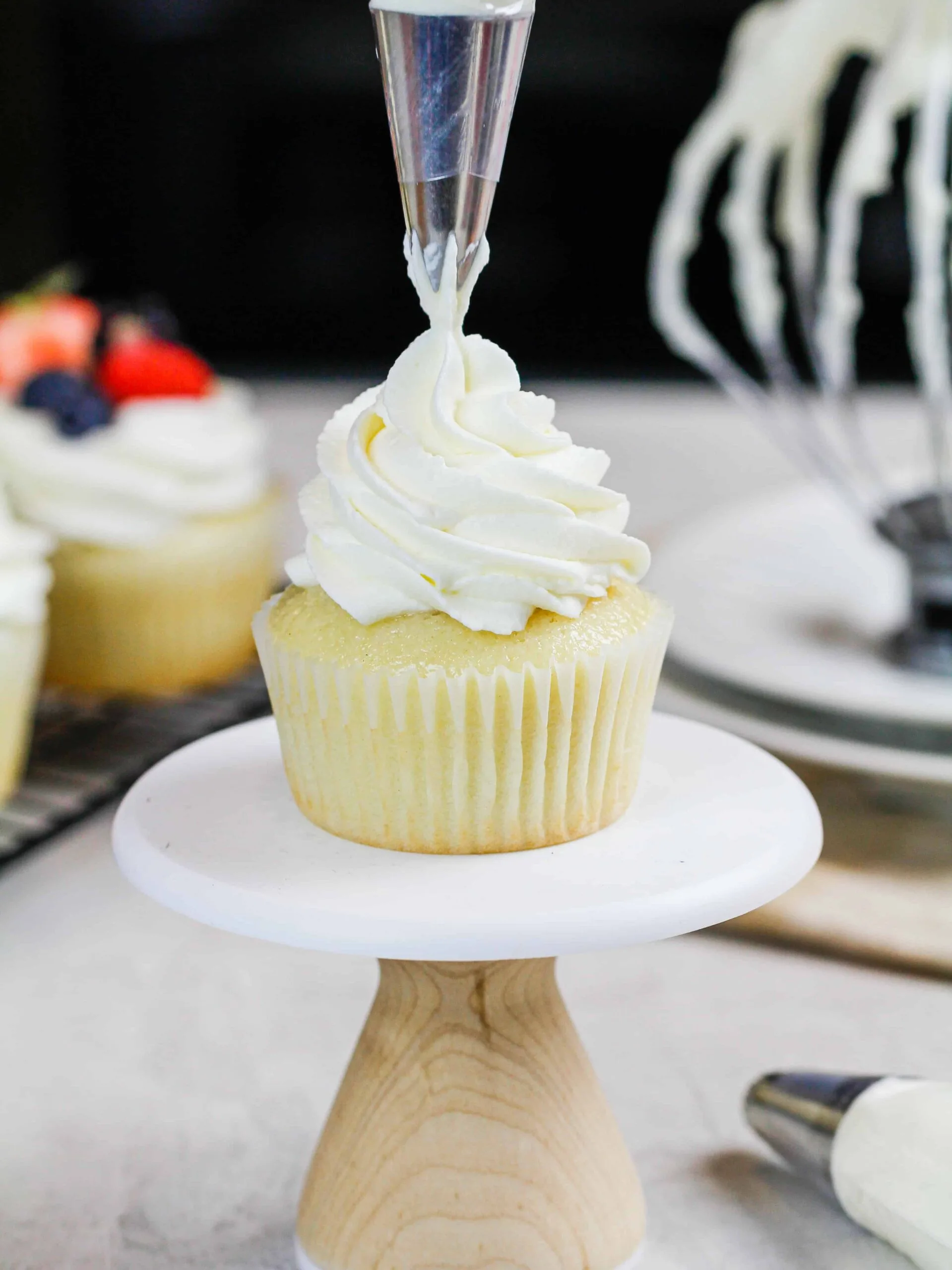 image of stabilized whipped cream frosting made with cream cheese being piped onto a cupcake