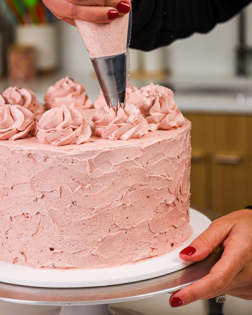 image of a cake that's being frosted with a strawberry Swiss meringue buttercream frosting