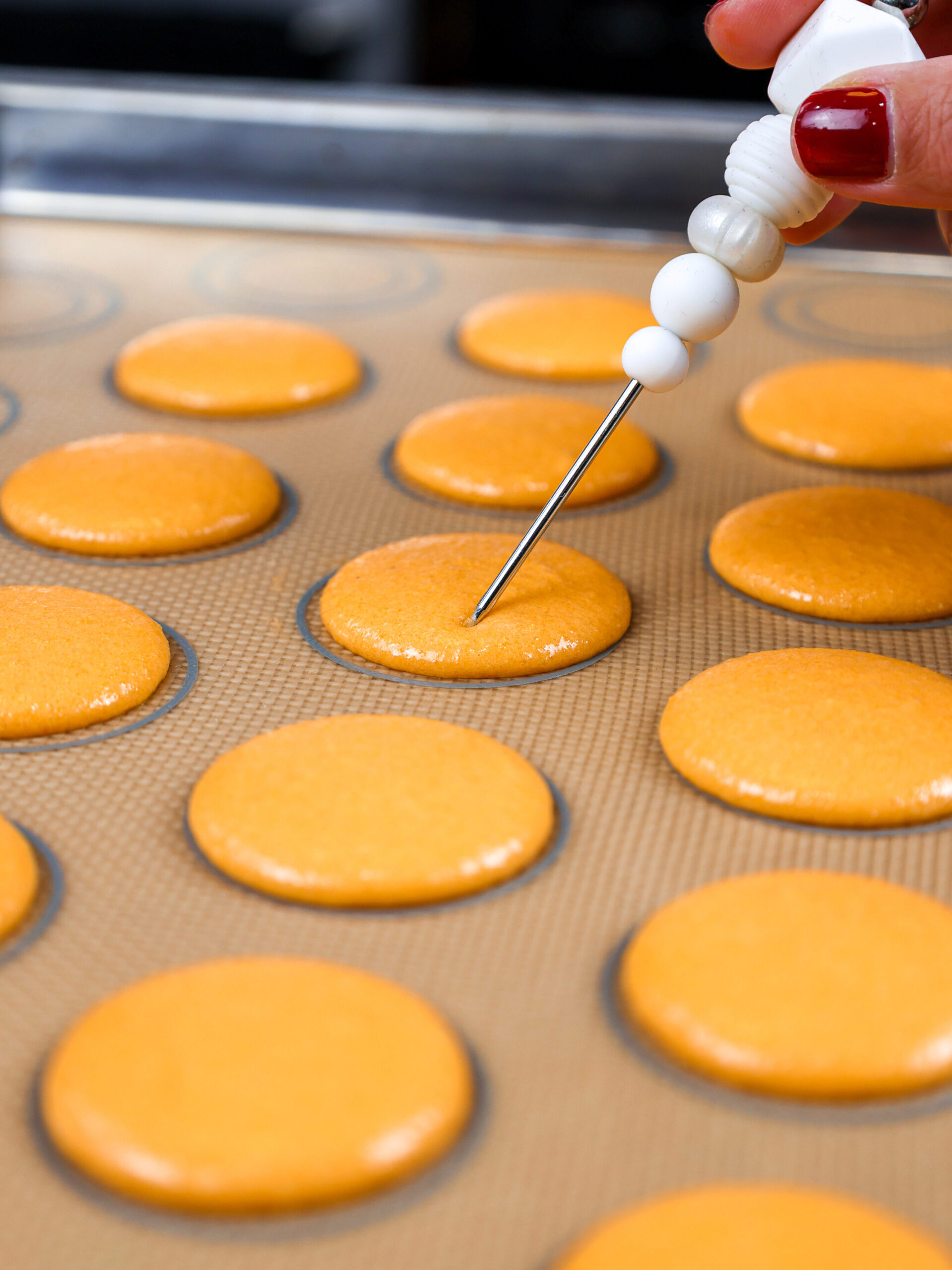 image of orange macaron shells resting after being banged on the counter