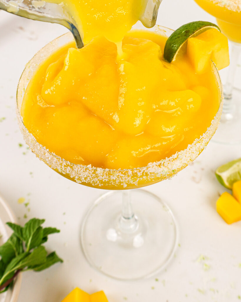 image of frozen mango margaritas being poured into margarita glasses