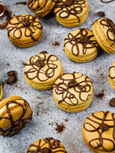 image of coffee macarons decorated with a drizzle of dark chocolate and a coffee bean