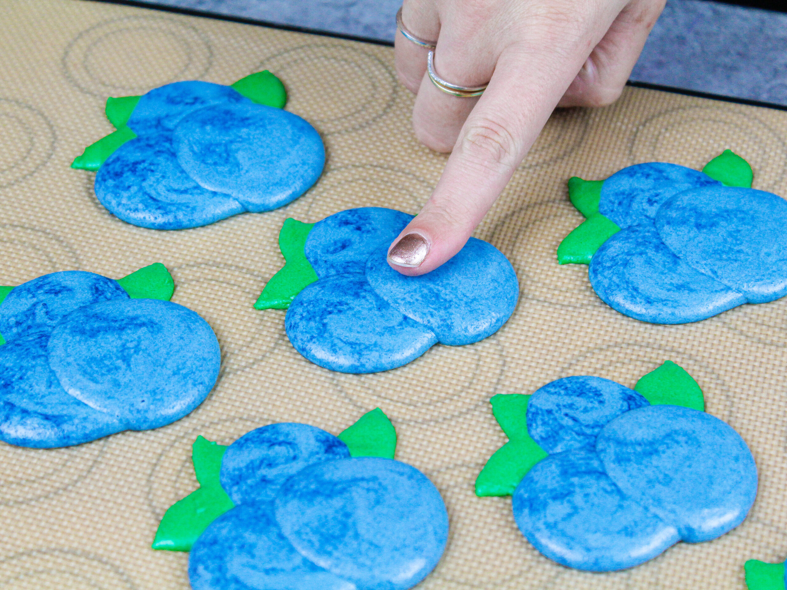 image of blueberry shaped macarons that have been piped and rested to form a skin before being baked