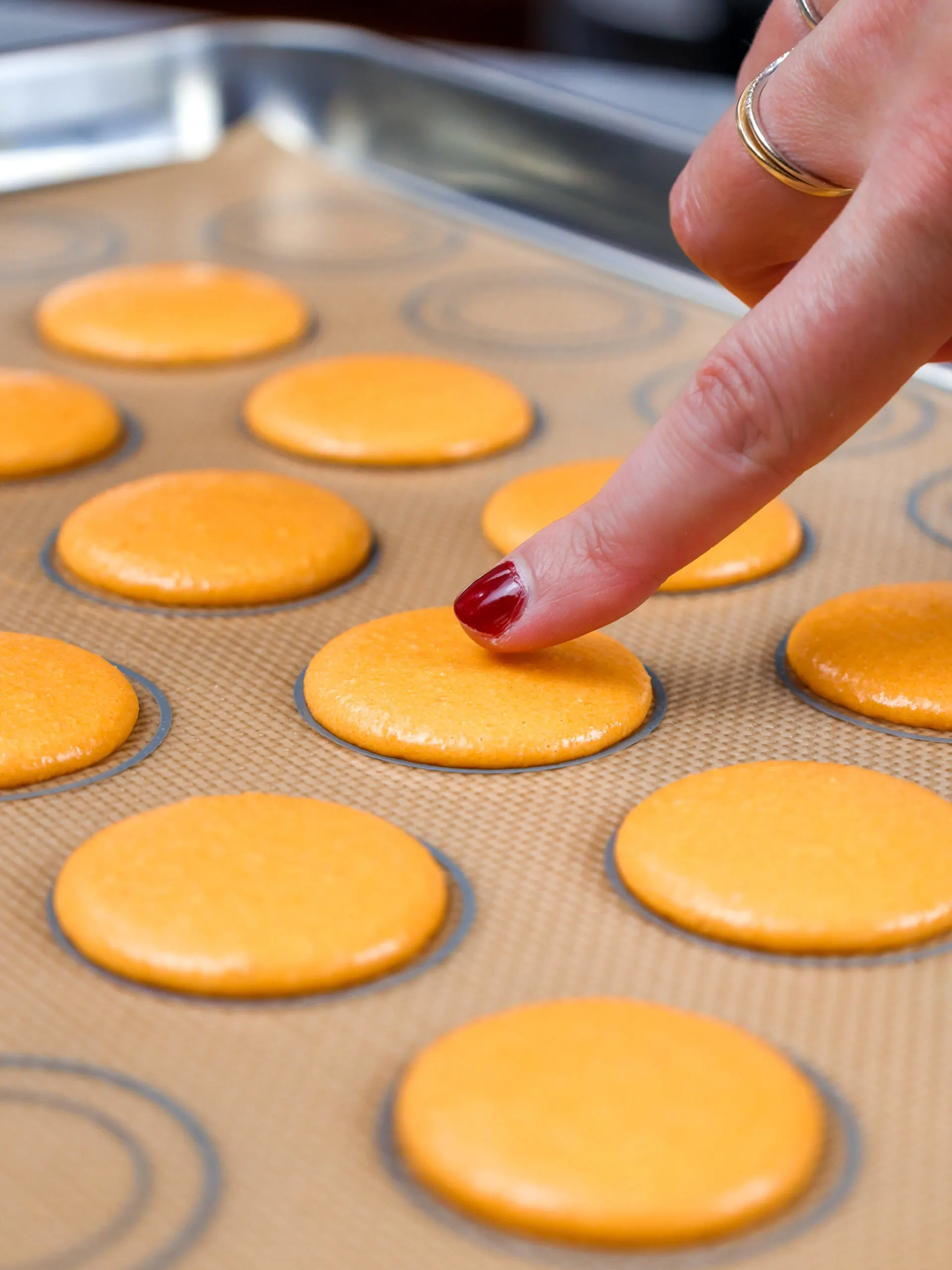 image of orange macaron shells that have rested and formed a skin before being baked