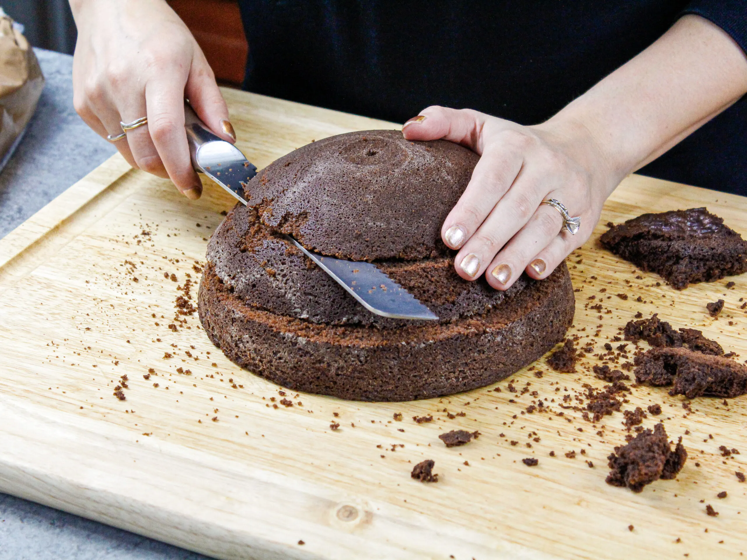 image of a round domed chocolate cake layer being torted into layers