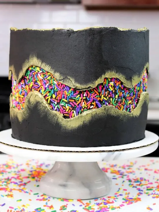 Sprinkle fault line cake, made with funetti cake layers and black cocoa buttercream frosting