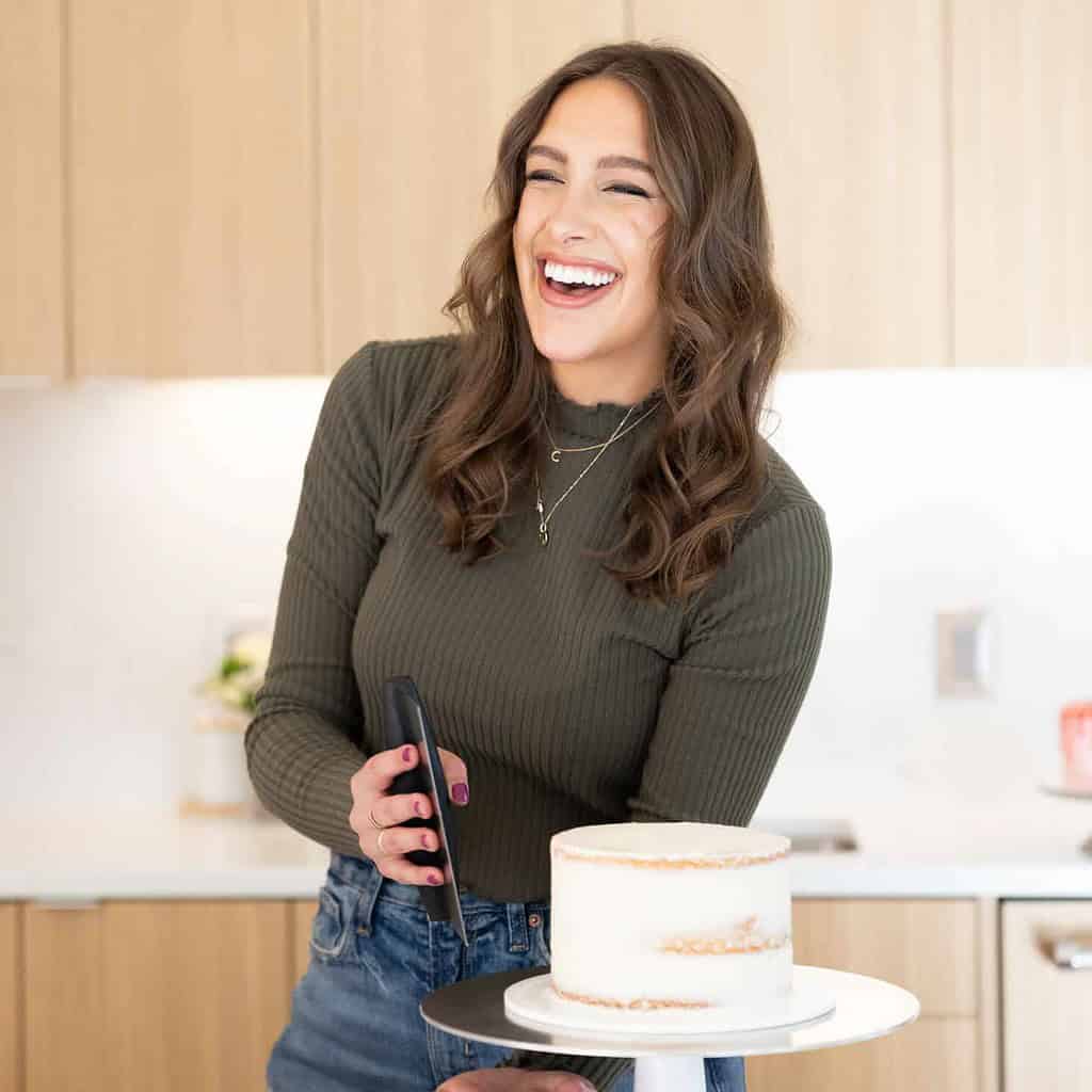 image of chelsey white of chelsweets crumb coating a cake with a bench scraper