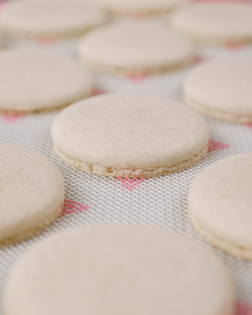 image of white macaron shells that have been baked and are cooling on a pan