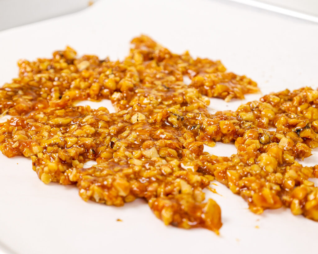 image of walnut brittle that's been cooked and is cooling on a piece of parchment paper