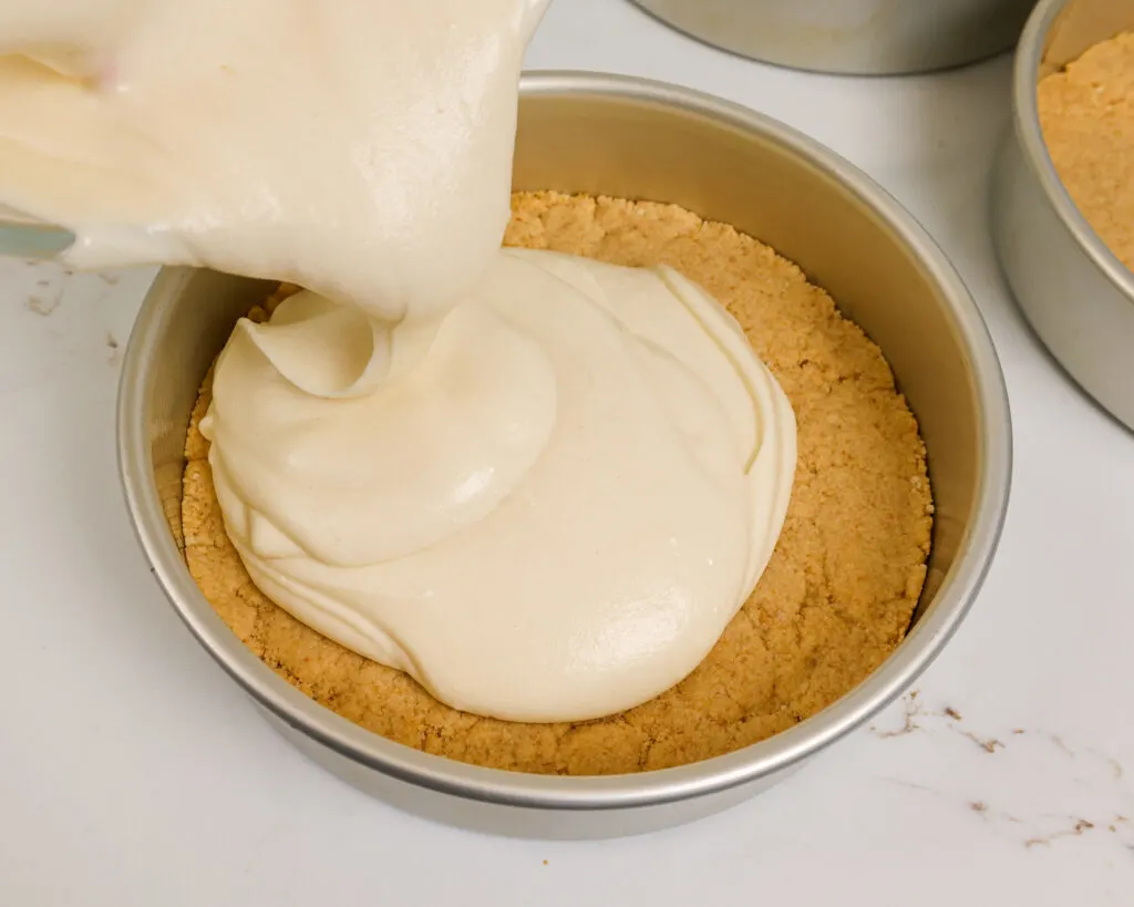 image of vanilla cake batter being poured on top of a shortbread crust