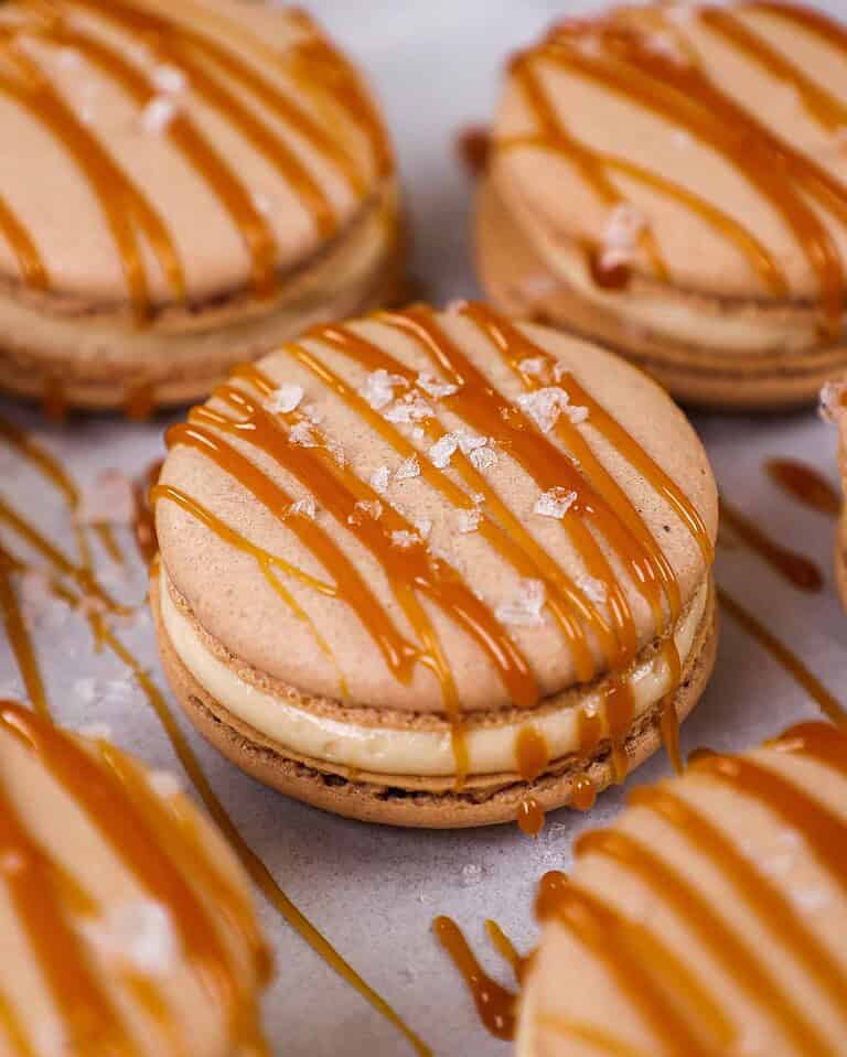image of a salted caramel macaron decorated with a drizzle of caramel and a sprinkle of flakey sea salt