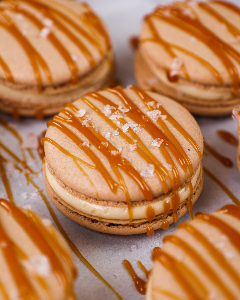 image of salted caramel macarons decorated with a drizzle of caramel and a sprinkle of flakey sea salt