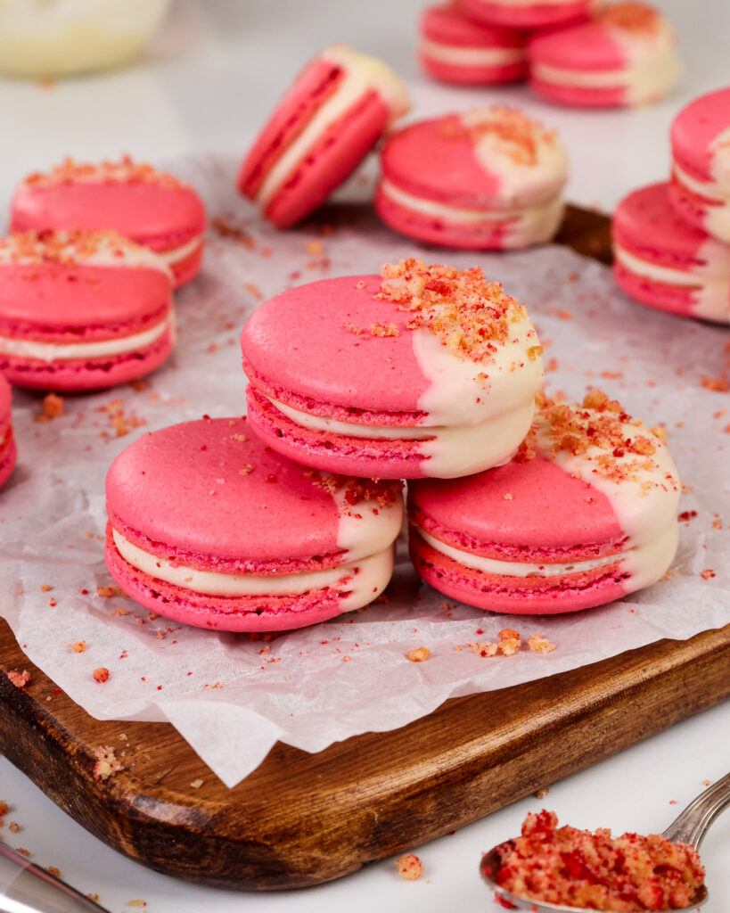 image of strawberry shortcake macarons that have been filled with strawberry jam and a mascarpone filling and topped with a strawberry shortcake crumble