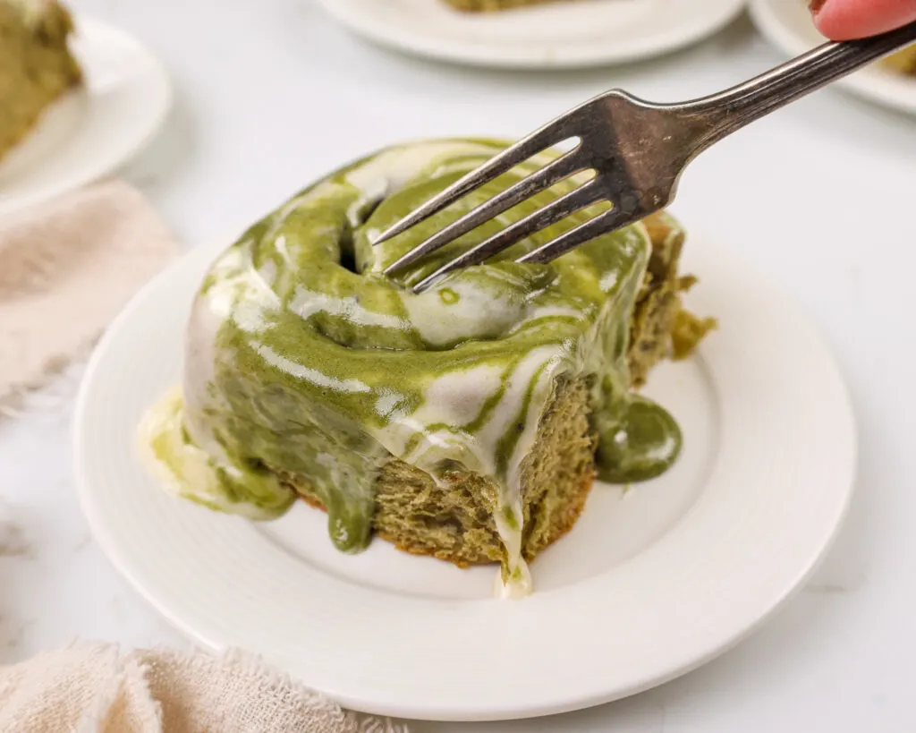 image of a warm matcha sweet roll on a plate that's about to be cut into