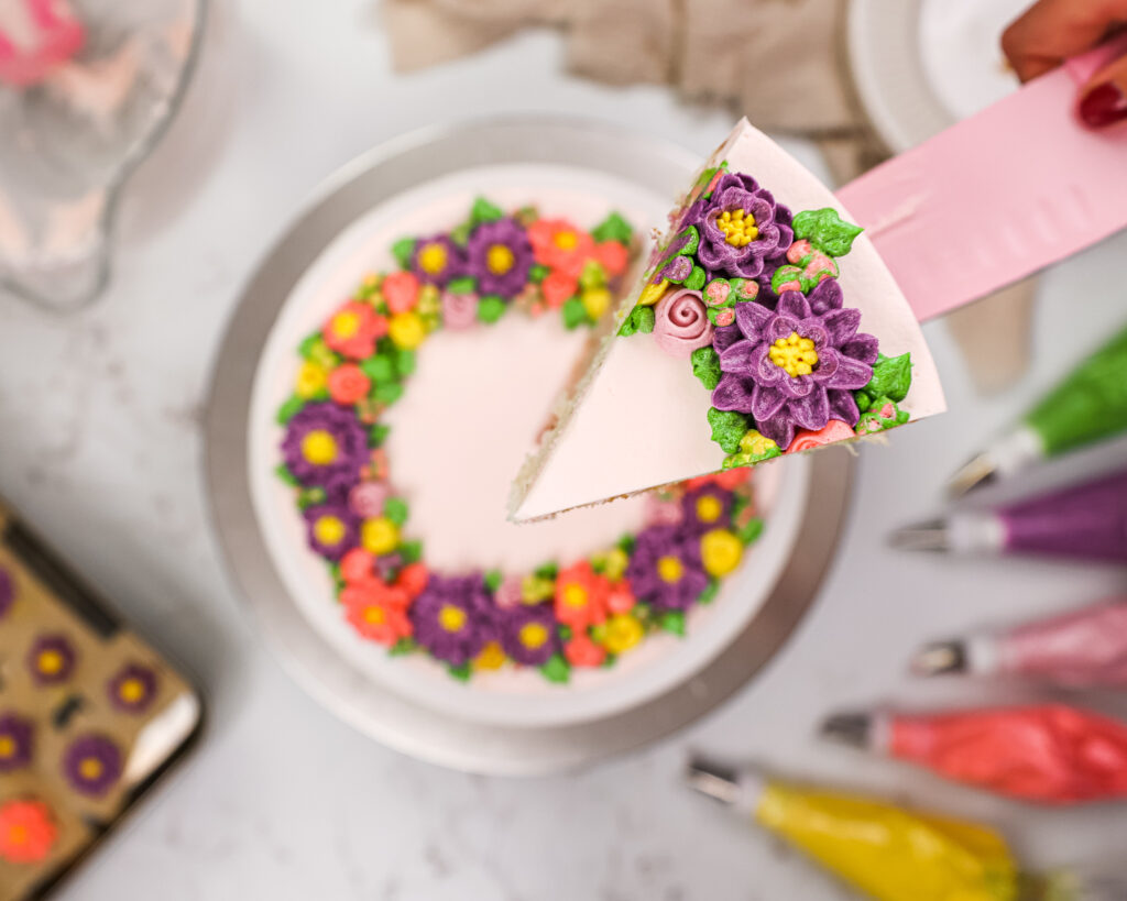 image of a slice of a buttercream flower cake being lifted up toward the camera to allow you to see more detail