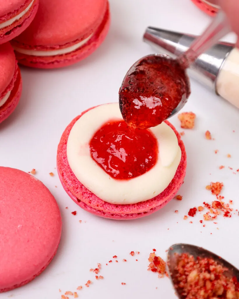 image of a strawberry shortcake macaron that's being filled with mascarpone frosting and strawberry jam