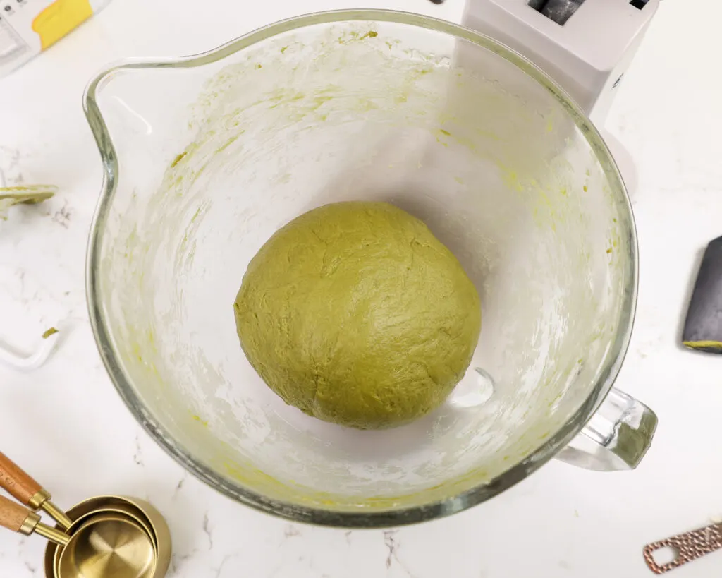 image of matcha dough that's been mixed in a kitchen aid mixer with a dough hook and is now ready to rest
