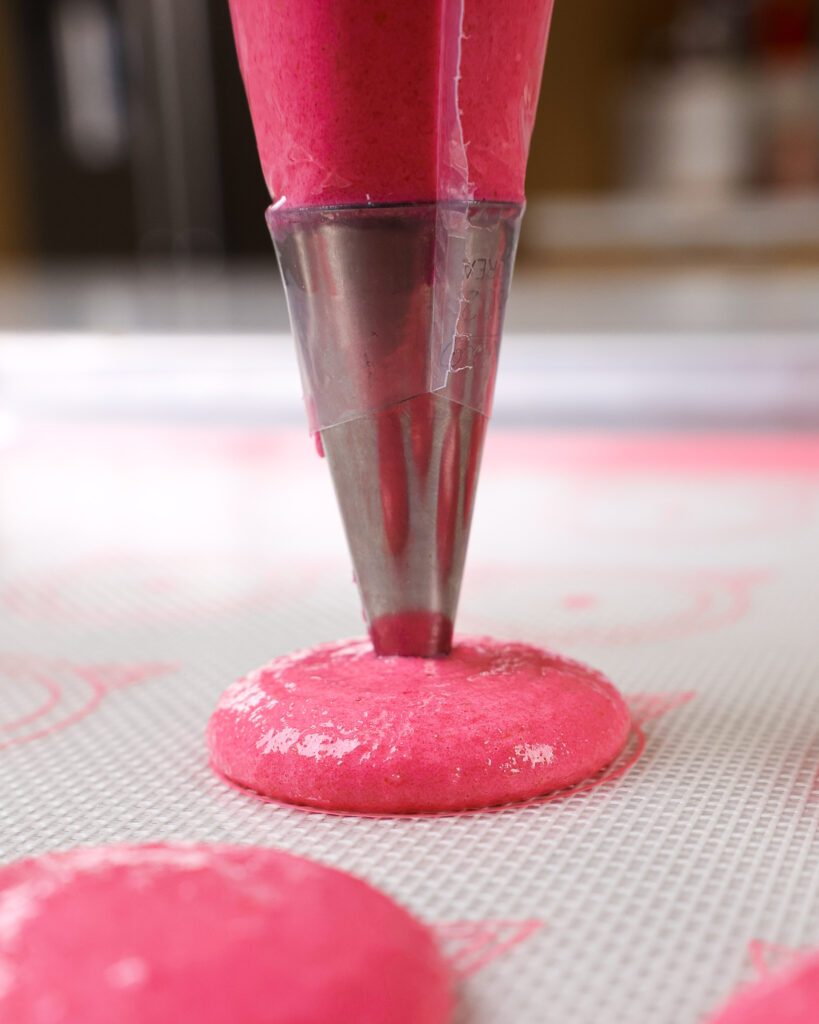 image of pink macaron shells being piped