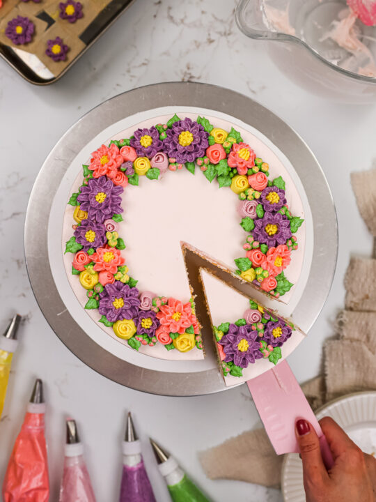 image of a buttercream flower cake that's been decorate with pink, purple and yellow buttercream flowers