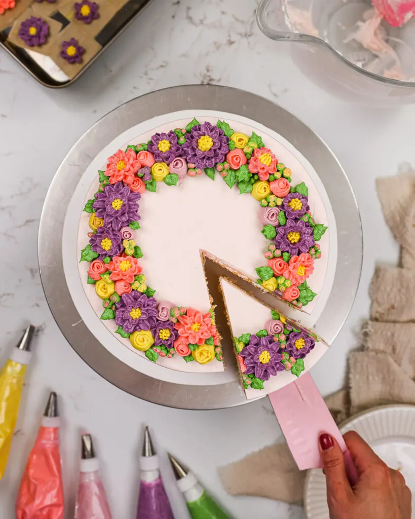 image of a buttercream flower cake that's been decorate with pink, purple and yellow buttercream flowers