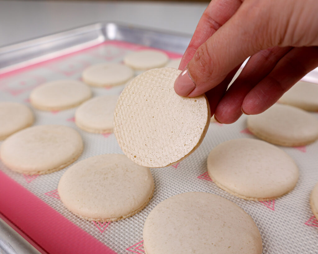 image of white macaron shells that have been baked properly and cleanly peel off the mat once baked and cooled